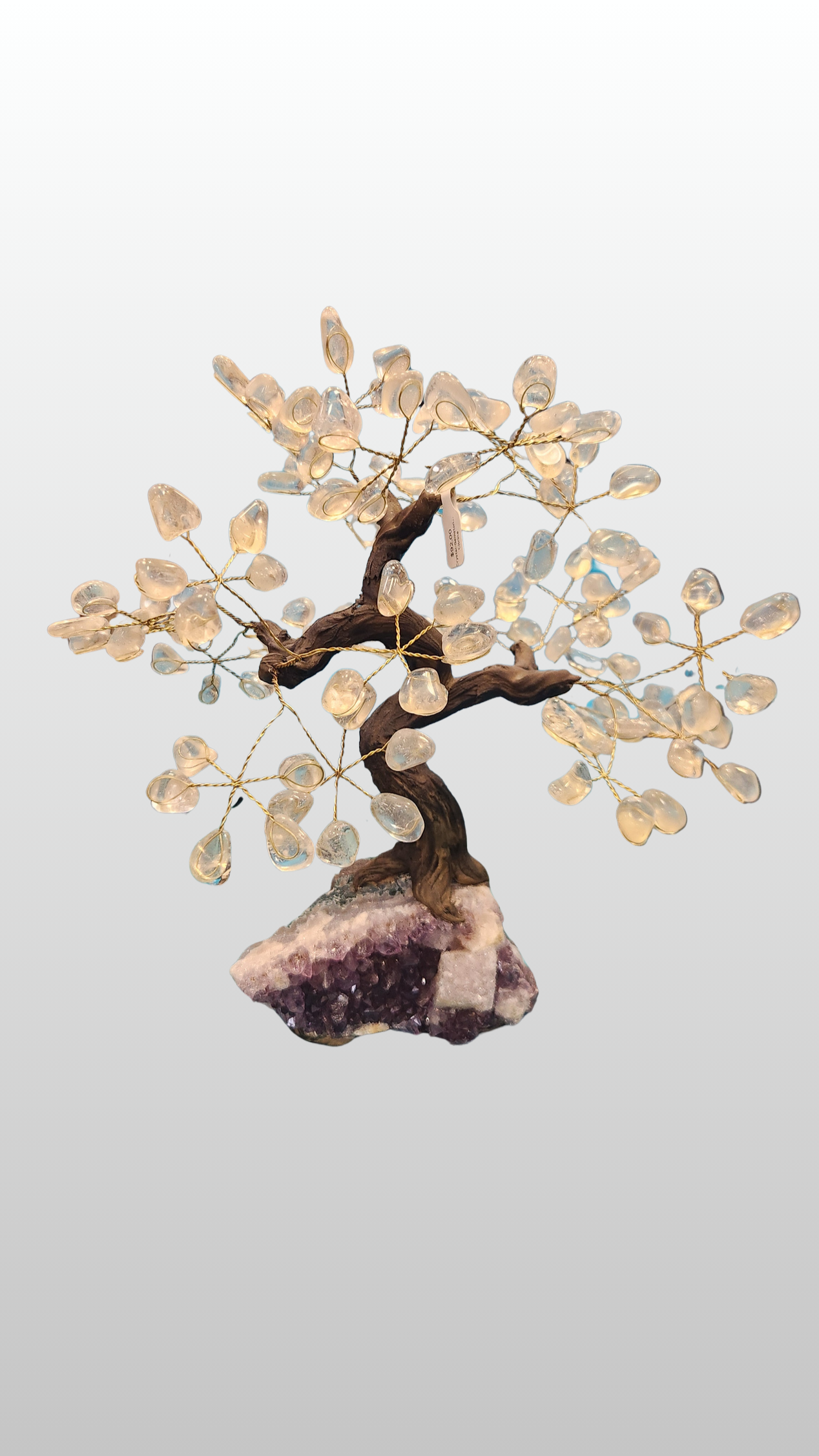 Decorative crystal quartz tree on a amethyst rock with a light gray background