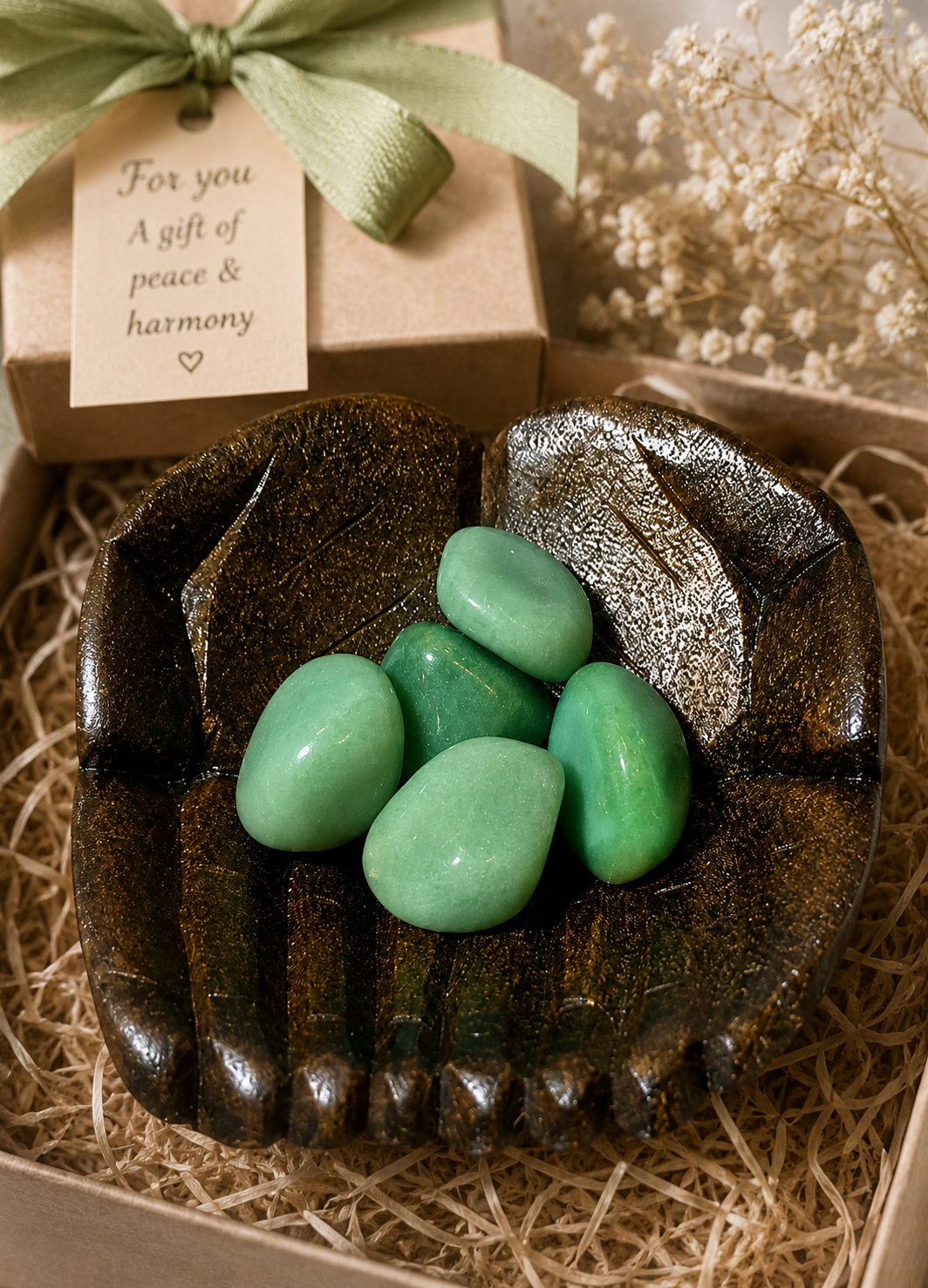 A refined still-life of polished aventurine stones presented in a hand-shaped wooden dish, symbolizing a thoughtful gift or personal keepsake. The composition conveys intention and care, with the natural textures and colors preserved exactly as in the original image.