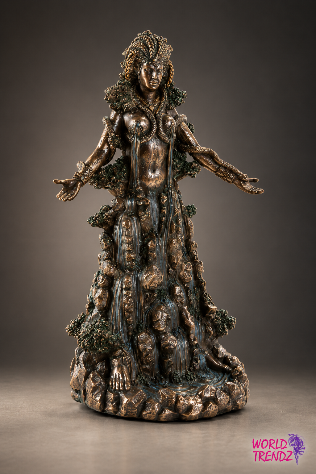 A bronze-finished statue of Goddess Danu with outstretched arms, styled with textured foliage and draped fabric, standing on a rocky base against a dark gray studio background.