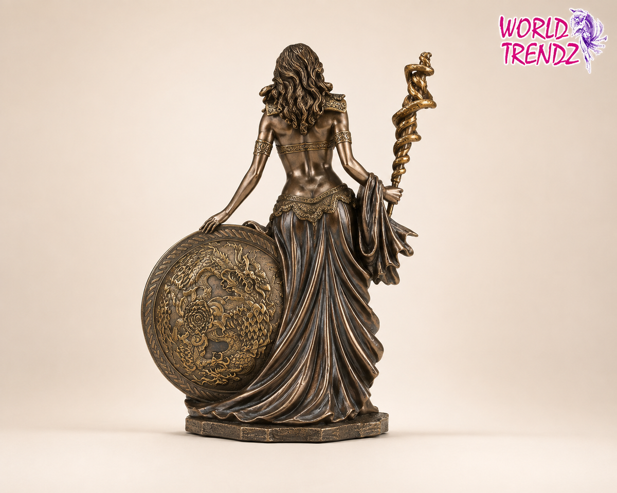 A bronze-finished decorative statue of a draped female figure Frigga, holding a globe and a twisted staff, shown against a plain beige studio background. A pink 'WORLD TRENDZ' watermark appears in the top right corner.