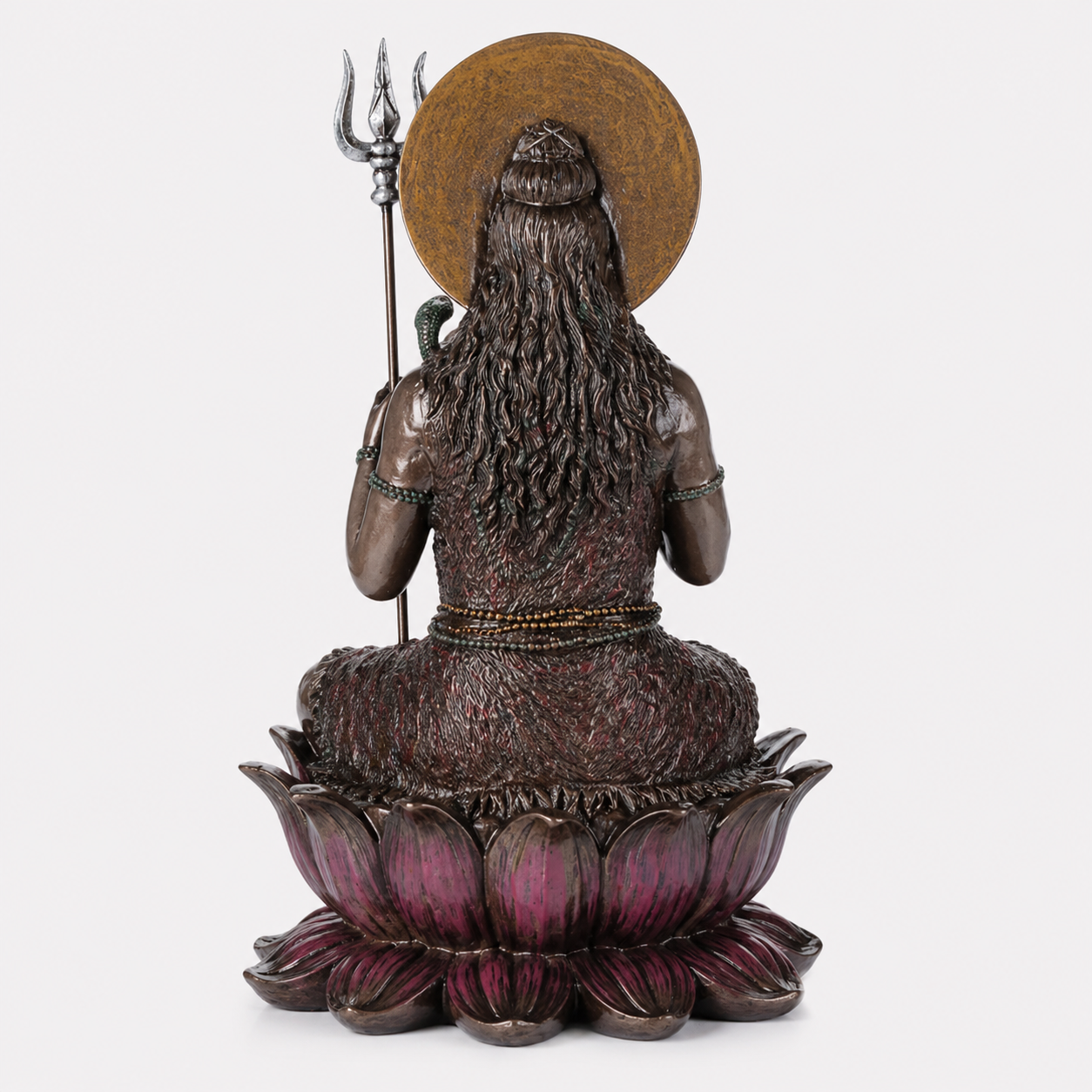 Statue of a seated Shiva with a trident on a lotus pedestal against a white background