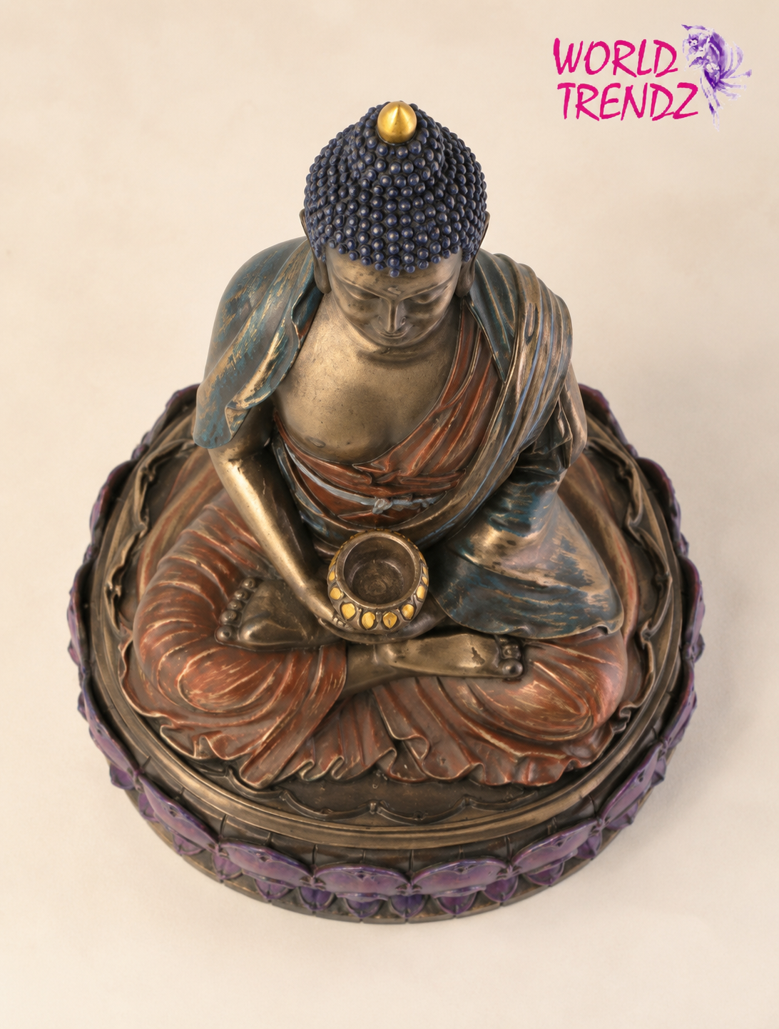 A seated Buddha Double Lotus Amitabha figurine with a bronze-toned finish, dark blue textured hair, rust-brown drapery, and purple lotus base details, photographed on a plain light beige background. A 'WORLD TRENDZ' logo appears in the top right corner.
