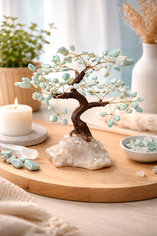 Decorative aventurine miniature tree on a rock with a candle and stones on a wooden surface