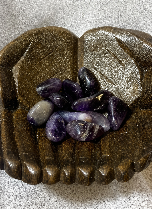 Decorative wooden hand with Amethyst stones on a textured surface