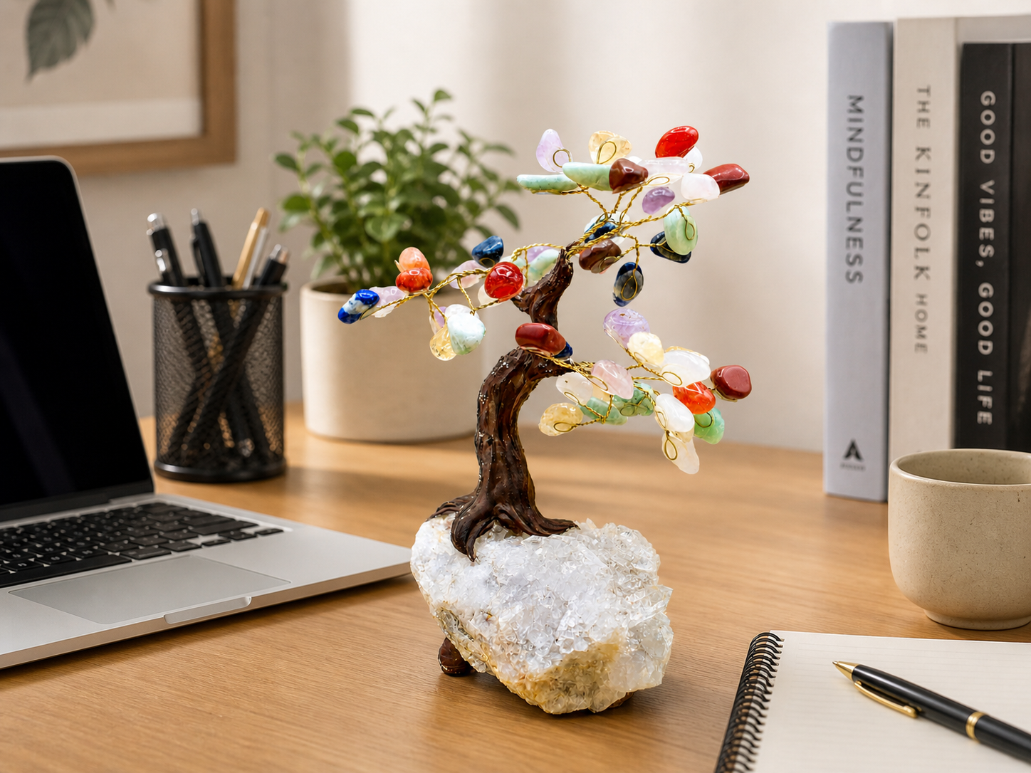 The chakra gemstone tree placed neatly on a clean office desk beside a laptop and notebook. 