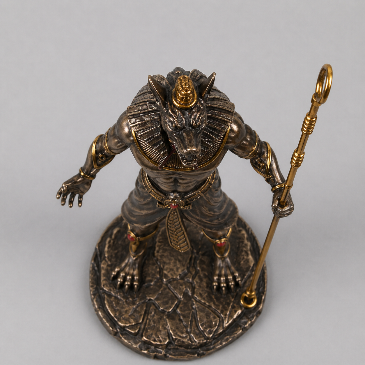 Statue of a Anubis with a gold headdress and staff on a gray background