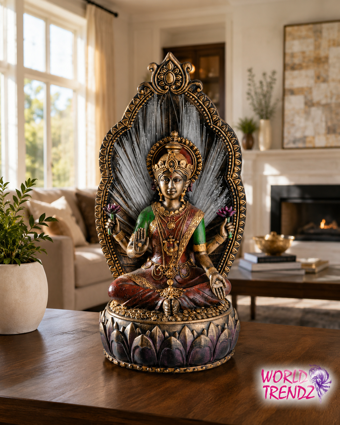 A decorative seated deity Lakshmi statue with ornate gold detailing, a dark gray arched backdrop, and purple lotus-style base details, displayed on a wooden table in a bright living room. A 'WORLD TRENDZ' logo appears in the bottom right corner.