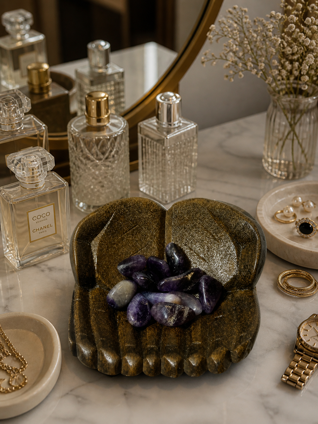 A vanity or dressing table scene with a mirror in the background. The carved bowl with ametrine stones is used as a decorative holder, placed among perfumes, rings, and small accessories. Soft diffused lighting reflects subtly on the polished stones, giving a chic and personal lifestyle feel.