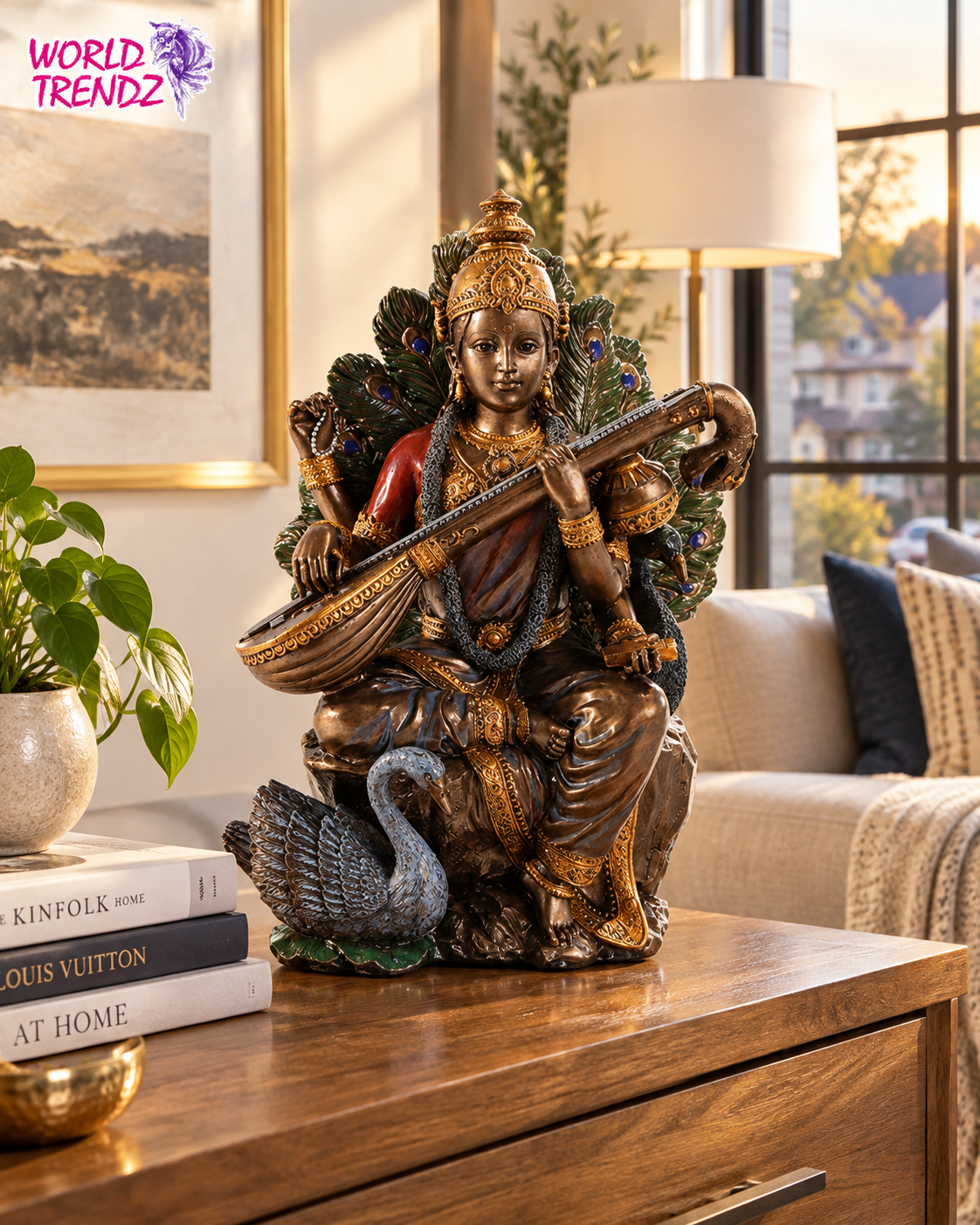 A bronze-finished statue of a Hindu goddess Saraswati seated on a peacock, holding a veena, displayed on a wooden table in a modern living room setting.