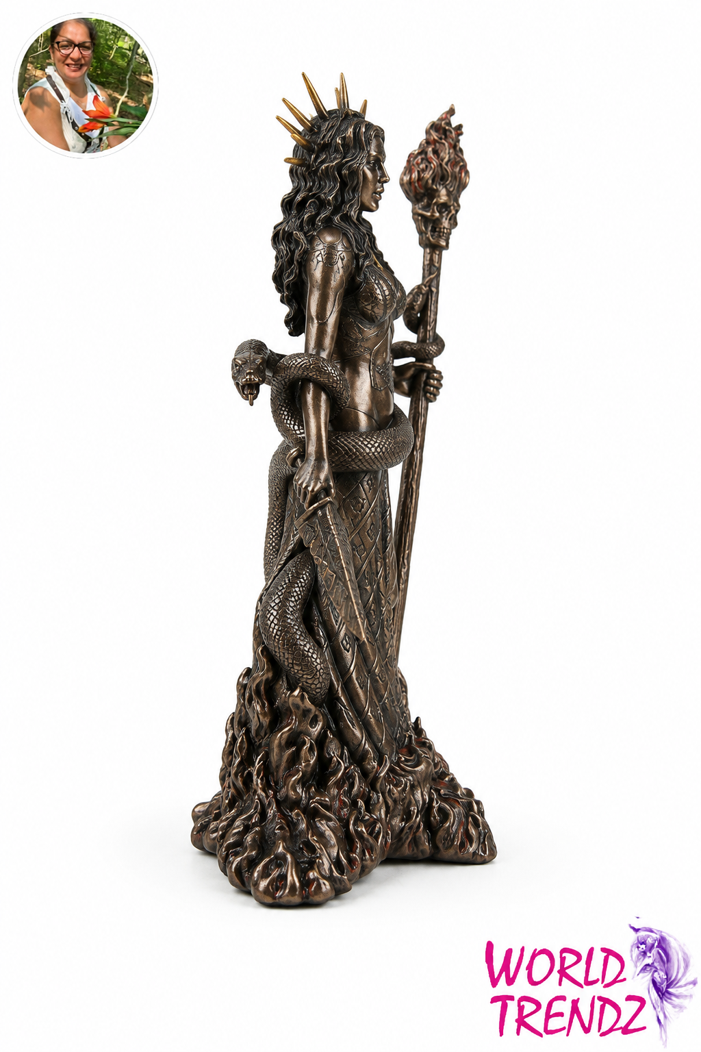 A bronze-finished statue of a crowned female figure Hecate with a snake draped around her waist, shown on a plain white background. A small circular inset photo appears in the top-left corner, and the text 'WORLD TRENDZ' appears in the bottom-right corner.