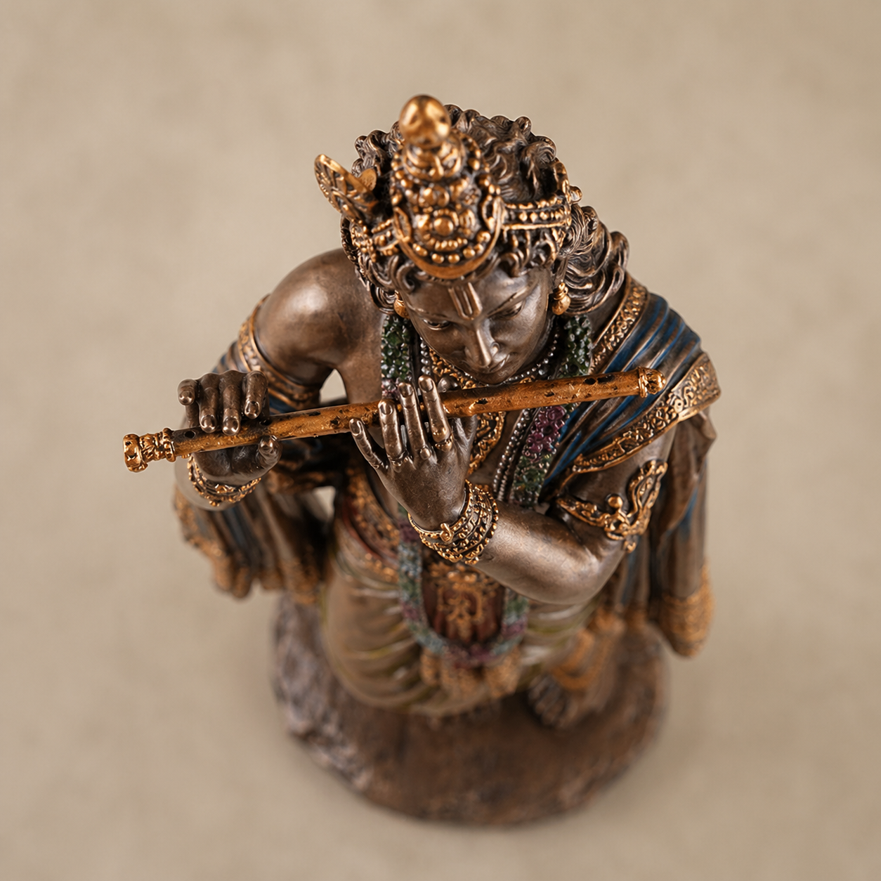 Statue of Krishna holding a staff on a beige background