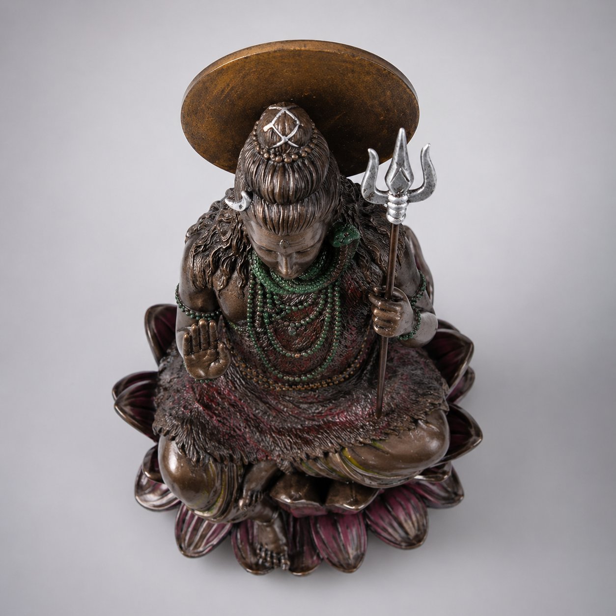 Statue of a seated Shiva with a trident on a gray background