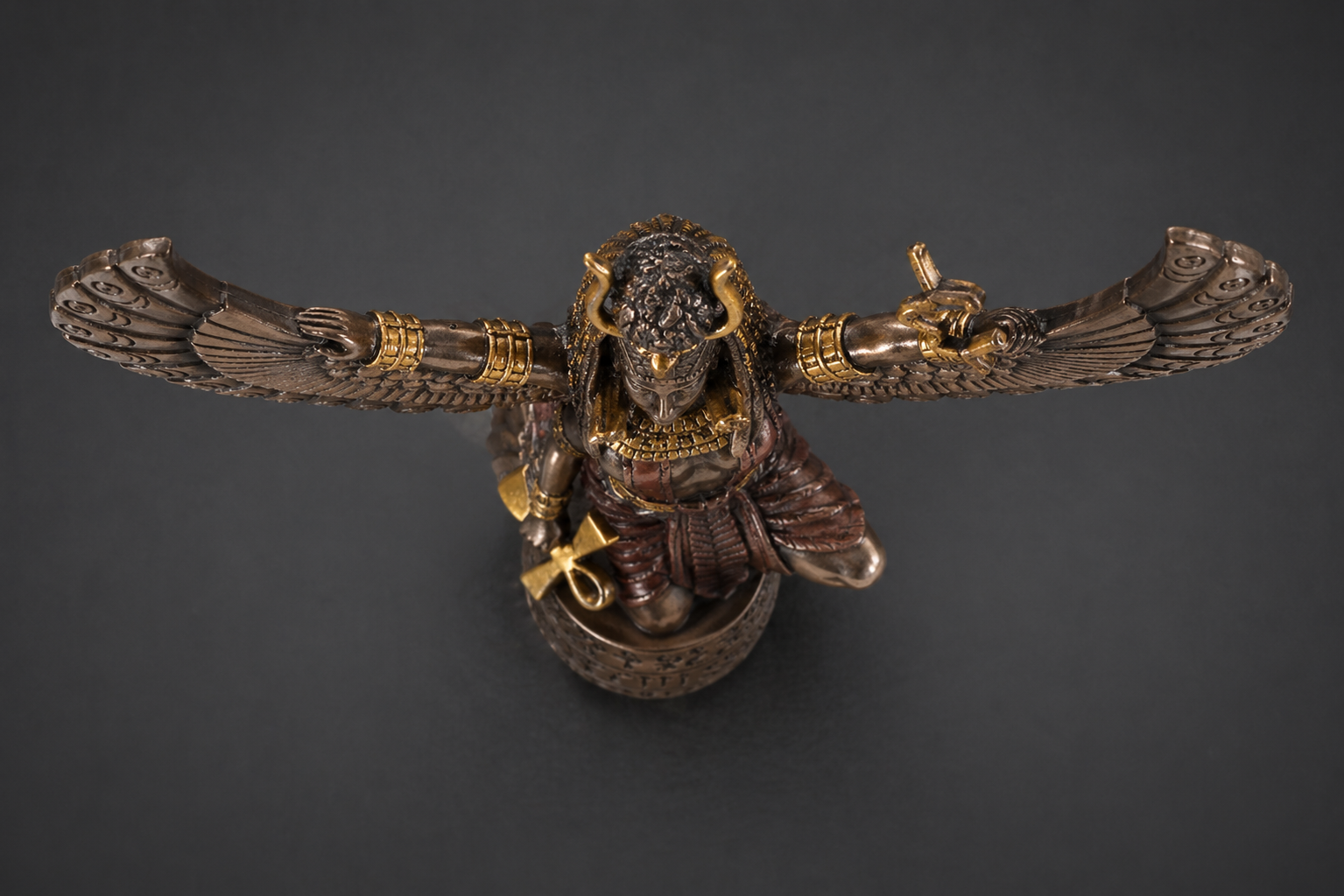 Decorative wall sculpture of Mother Isis with gold accents on a dark
