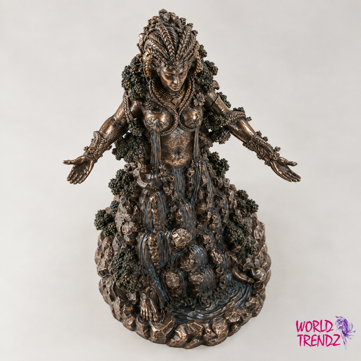 A detailed Goddess Danu with outstretched arms, styled as an earth goddess with foliage and rocky textures, finished in a dark bronze metallic color with blue undertones. The 'WORLD TRENDZ' logo is visible in the bottom right corner.