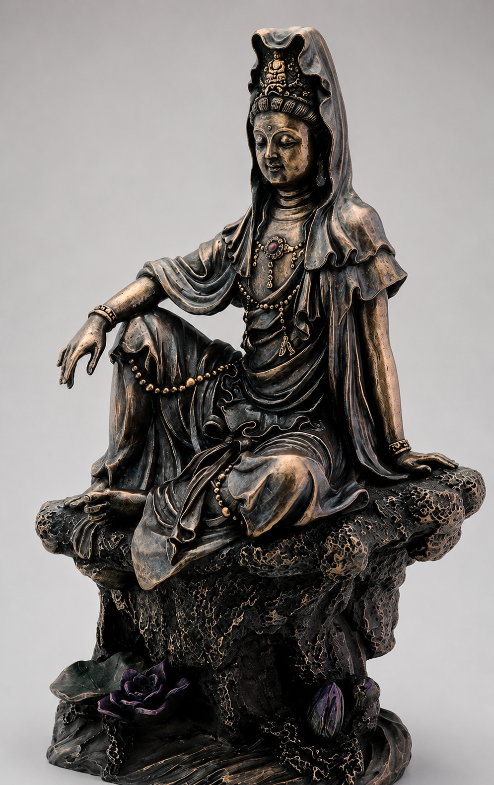 Bronze statue of Guanyin a seated figure on a gray background