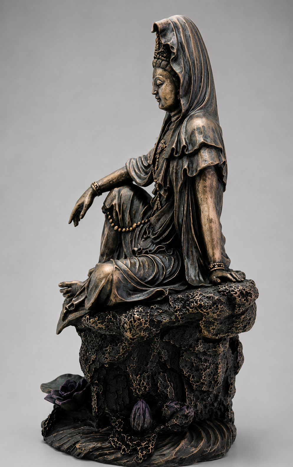 Bronze statue of Guanyin a seated figure on a gray background