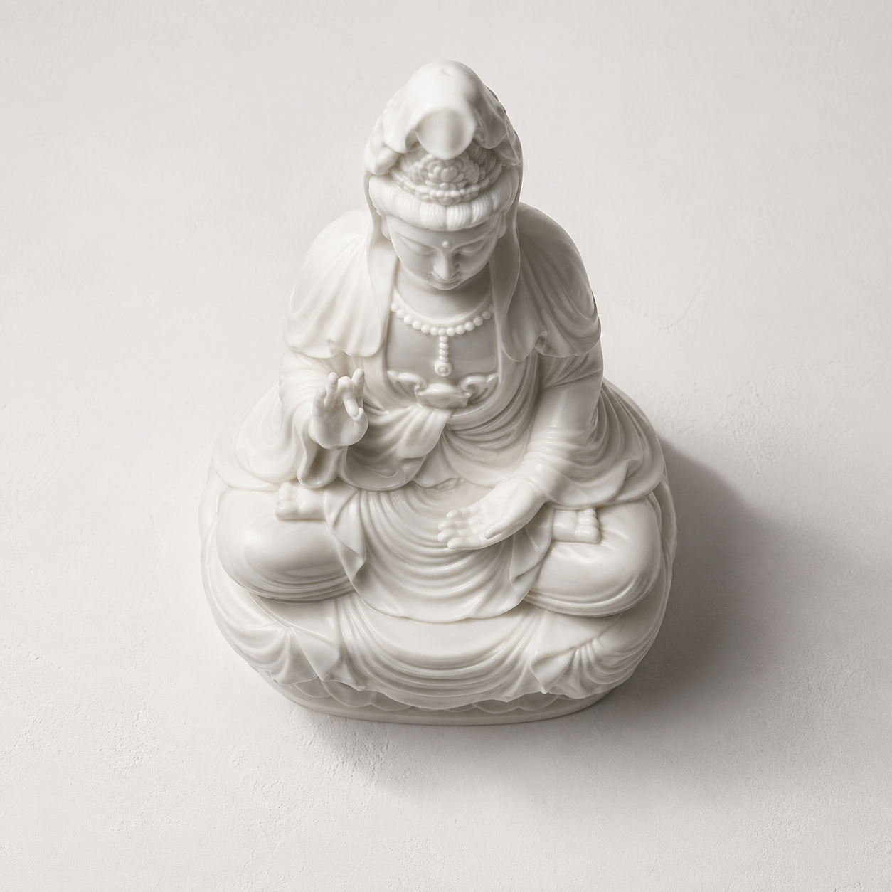 White ceramic statue of Kuanyin on a light gray background