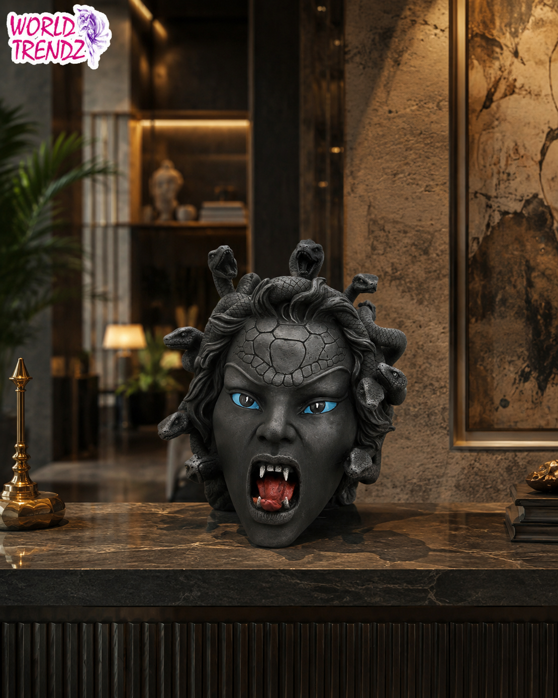 A dark gray Medusa head bust with glowing blue eyes, sharp fangs, and snake-like hair, displayed on a marble counter in a luxurious interior setting. A 'World Trendz' logo is visible in the top-left corner.